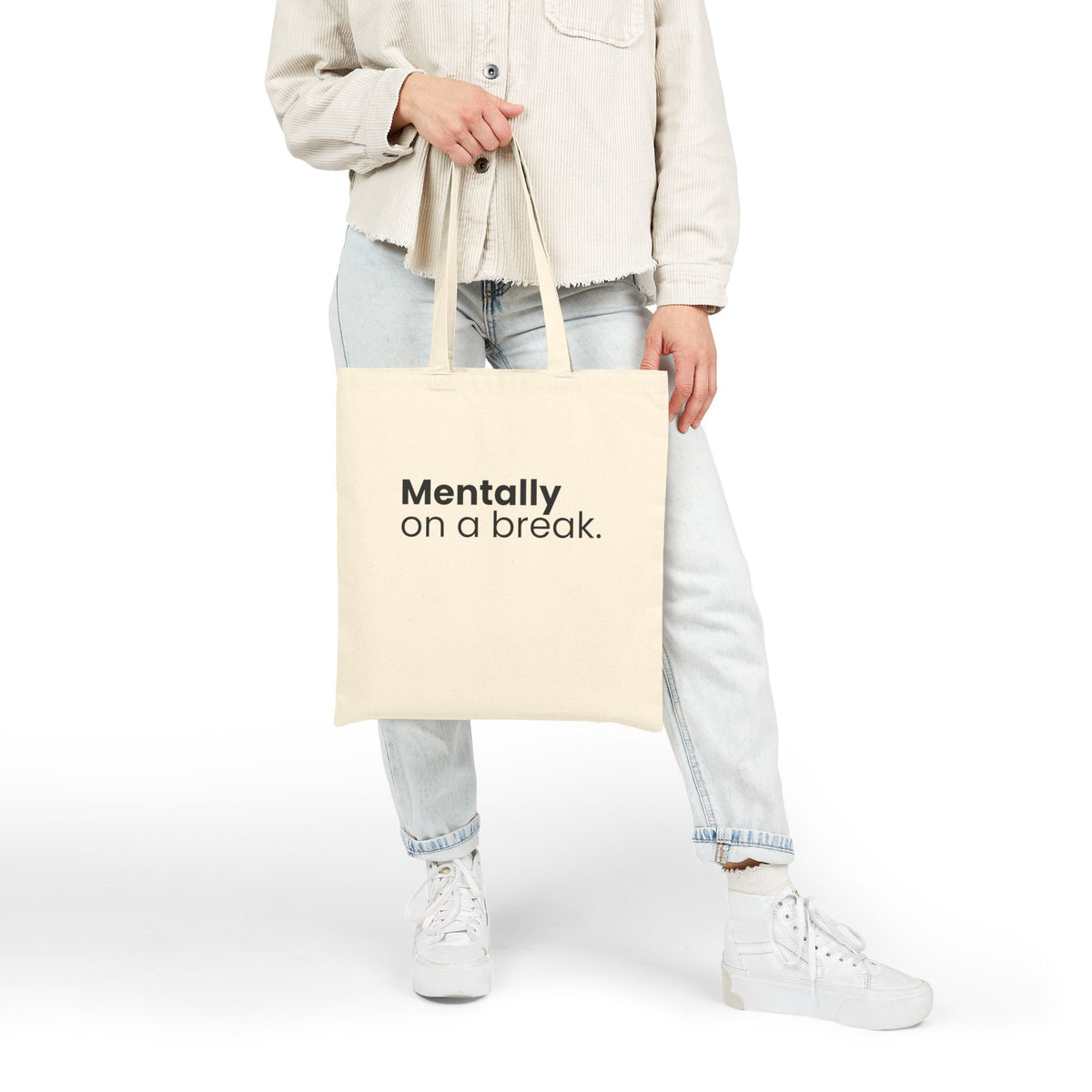 Person holding a beige canvas tote bag with "Mentally On a Break" statement design against a plain background